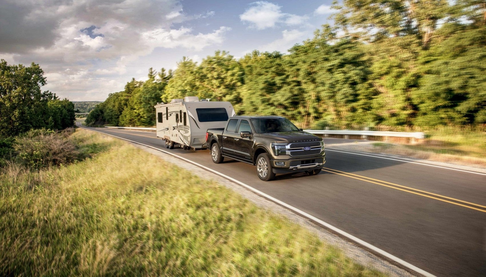 Ford F-150 with trailer hitched driving along scenic road