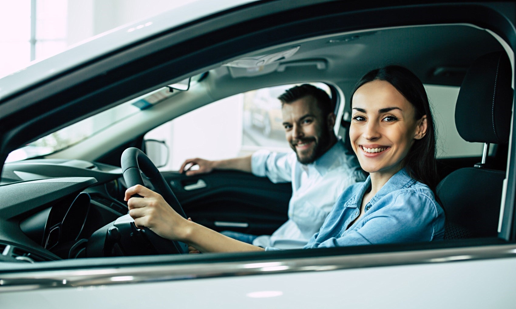 Couple smiling behind the wheel of their new pre-owned vehicle