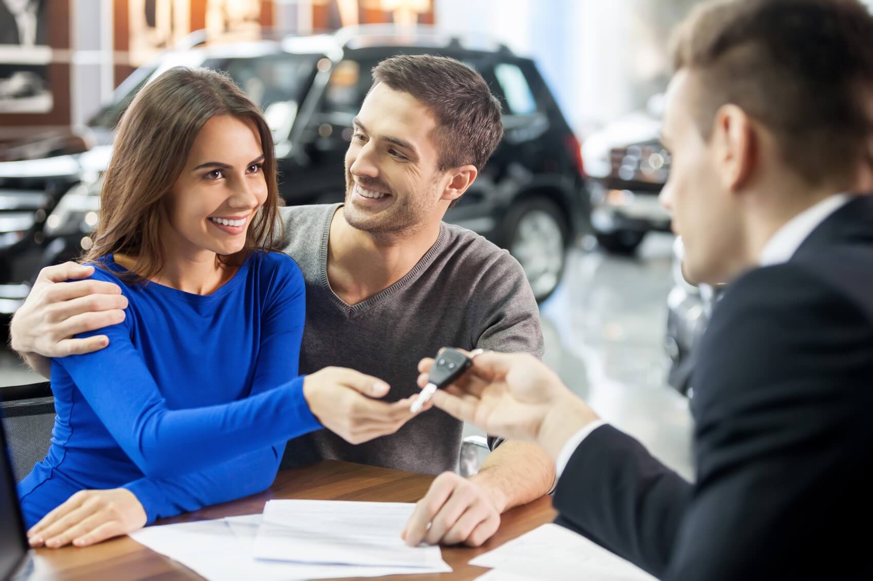 Ford Finance Center team member handing over keys to couple who just signed paperwork for a new Ford vehicle