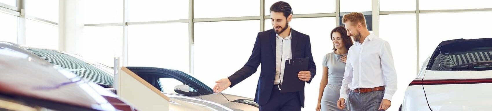 Ford Car Salesman showing couple Used cars in Ford showroom